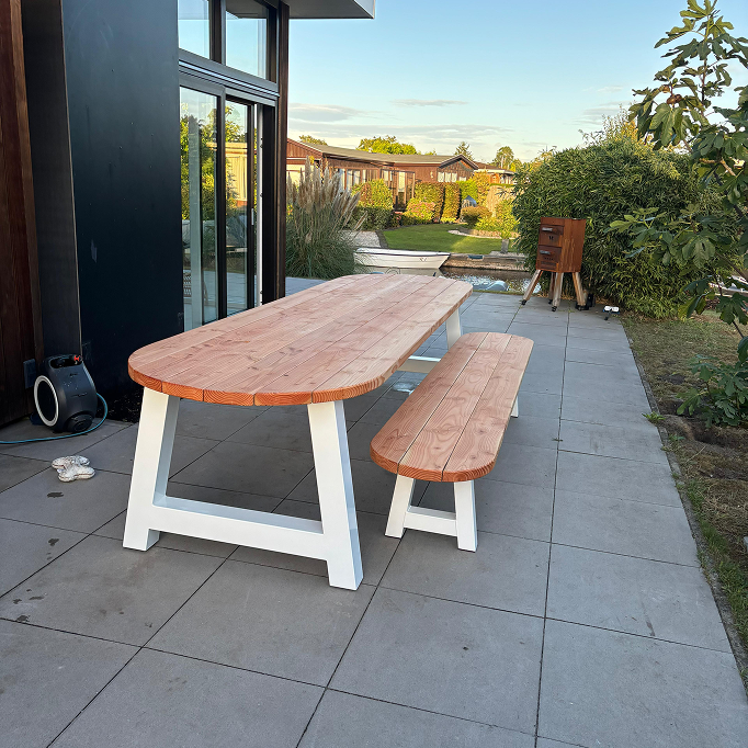 Tuintafel van douglas hout met witte gepoedercoate poten staand op terras in de achtertuin